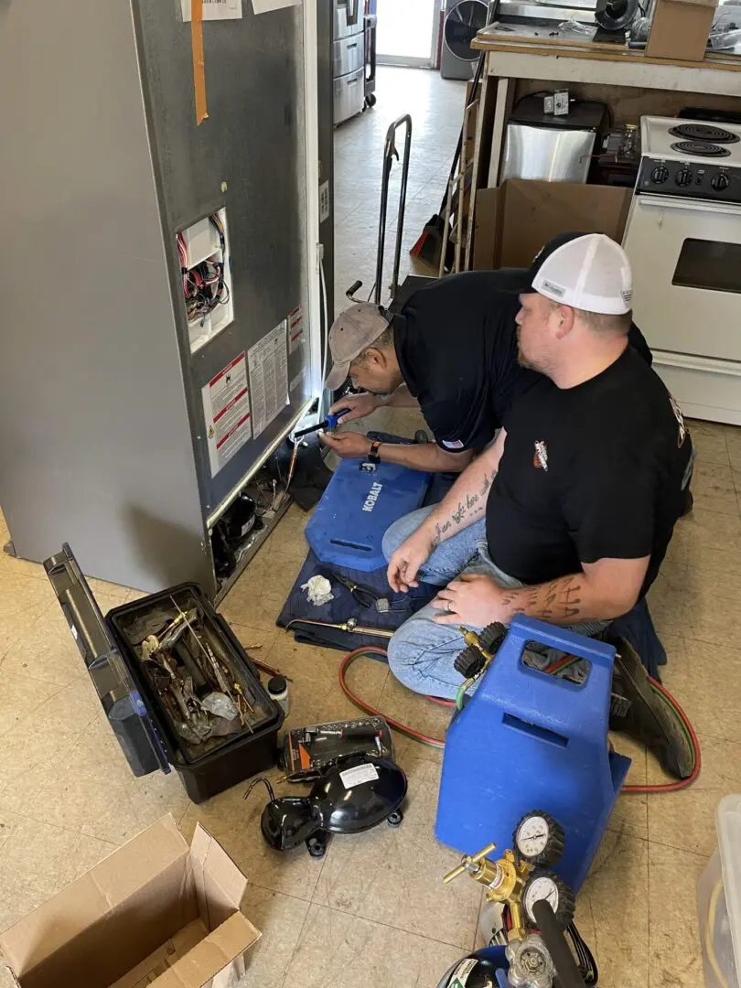 Technicians repairing commercial refrigerator unit