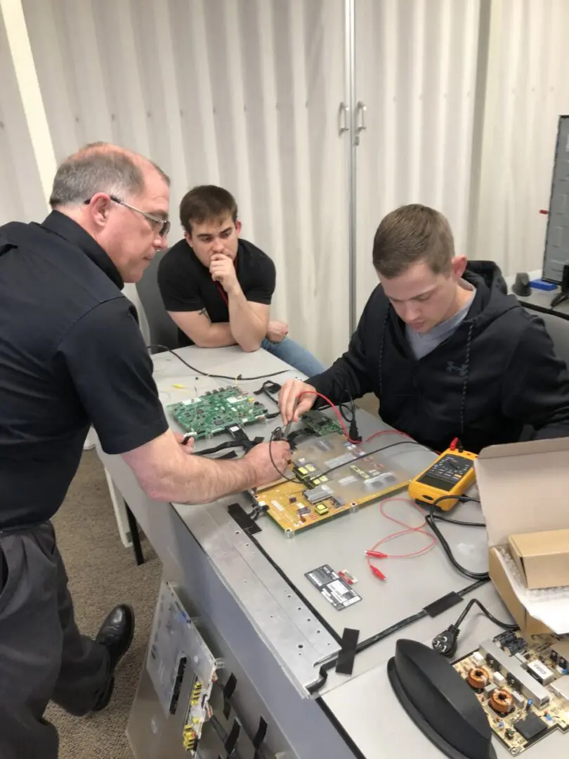 Instructor guiding students on electronics project